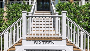 Eine Treppe führt zu einem weißen Gebäude, auf den Stufen ist das Wort "SIXTEEN" zu sehen.