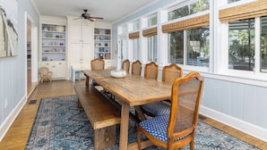 Ein Esszimmer mit Holztisch, blau gemusterten Stühlen und einem blauen Teppich.