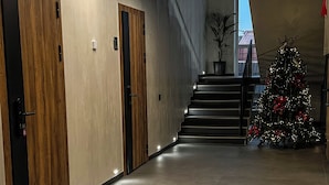 A modern hallway with a wooden door, a staircase, and a Christmas tree. - ForRest Cozy Apartments Minsk (Minsk)