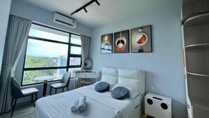 A hotel room with a bed, a desk, chairs, a window with a view, and artwork on the wall. - JQ PREMIER SUITES T1 L07 (Kota Kinabalu)
