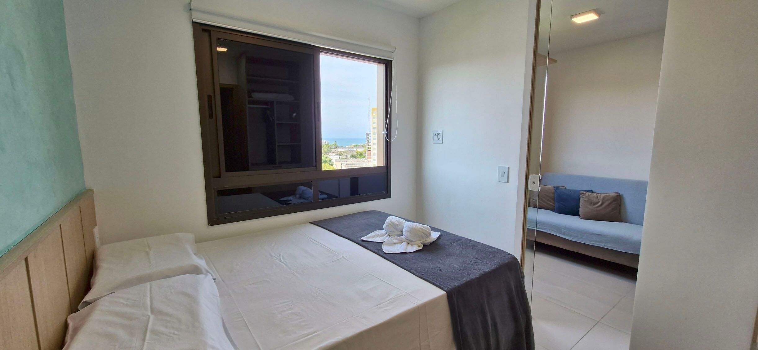 Habitación de hotel con cama, ventana con vistas, sofá y una mesita con toallas.