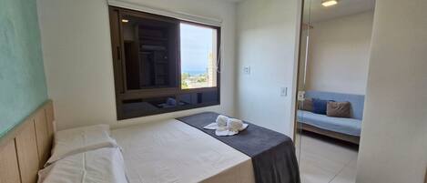 Habitación de hotel con cama, ventana con vistas, sofá y una mesita con toallas.
