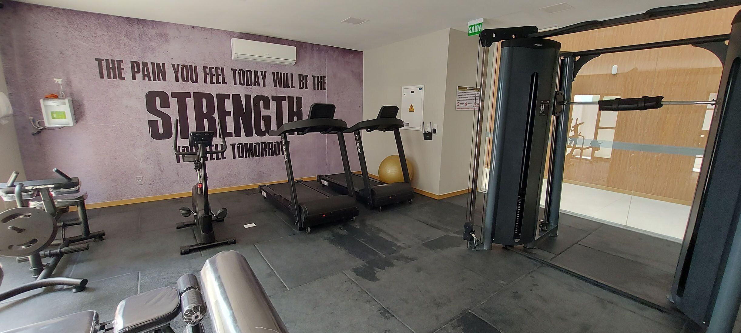 A gym with treadmills, a squat rack, and a yoga ball.