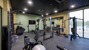 A gym with various exercise equipment, a mirror, and a window providing a view of the outside. - Holiday studio with balcony, indoor pool, sauna (Polanica Zdroj)