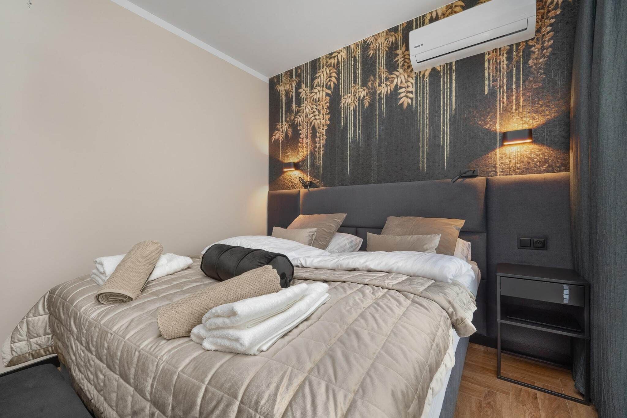 Ein modernes Schlafzimmer mit einem großen Bett, einer Wand-Klimaanlage und einem Nachttisch mit Lampe.