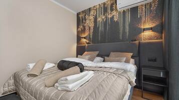 Ein modernes Schlafzimmer mit einem großen Bett, einer Wand-Klimaanlage und einem Nachttisch mit Lampe.