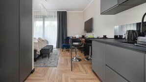 Una habitación de hotel moderna con kitchenette, un comedor y una cama con vistas.