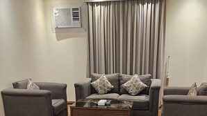 A living room with two grey sofas, a glass coffee table, and a wooden floor.