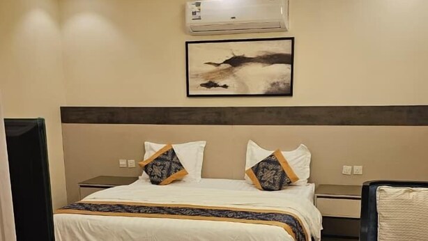 A hotel room with a bed, bedside tables, a desk, and a chair.