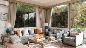 Un salon moderne avec un canapé, des fauteuils, une table basse en verre et un tapis à motifs.