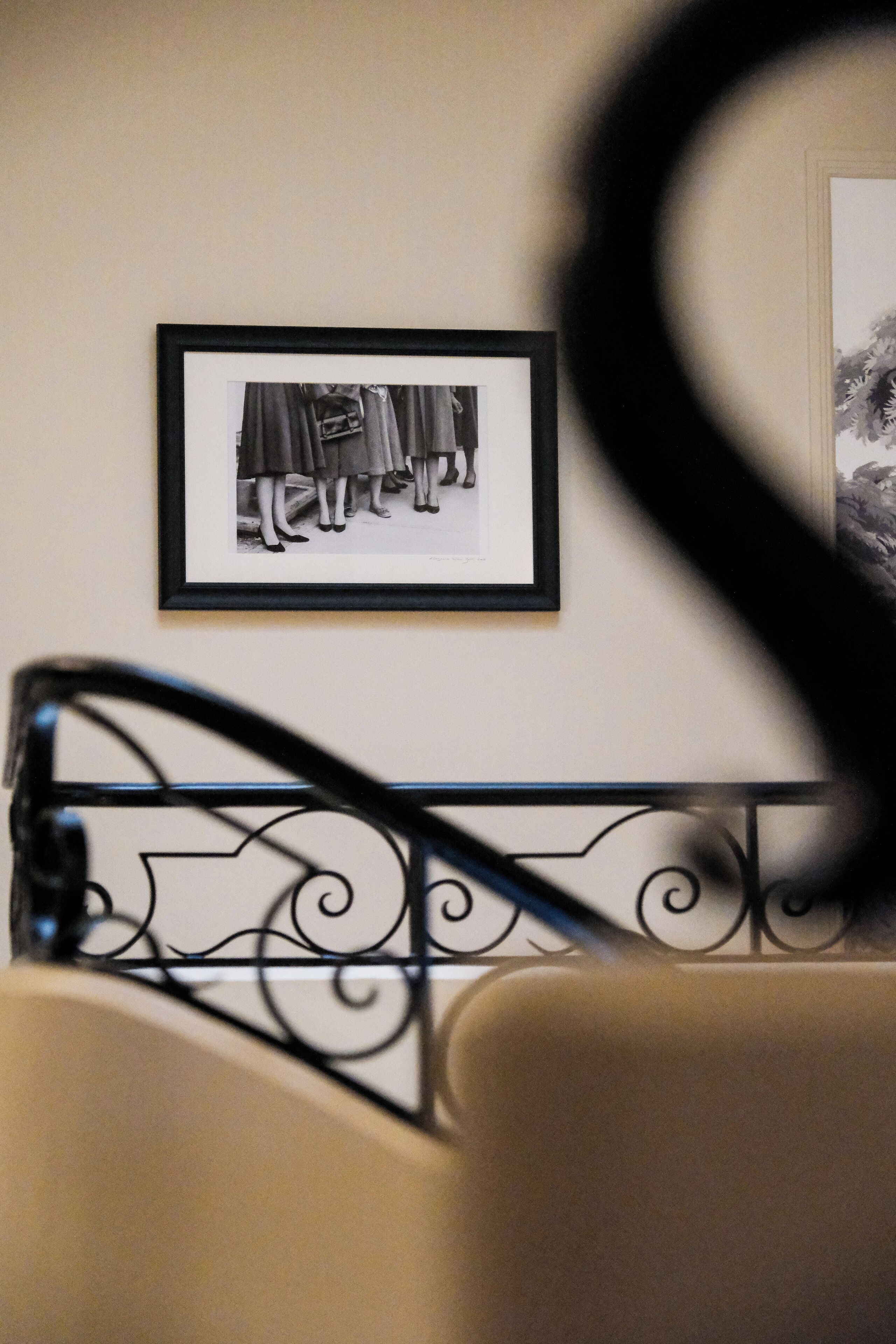 Una fotografia in bianco e nero incorniciata appesa al muro, una ringhiera metallica e una sedia color beige.
