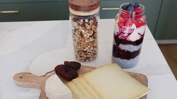 A wooden board with cheese, dried fruits, and nuts.
