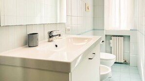 A bathroom with a white sink, a mirror, a toilet, and a radiator. - 8th floor - Milano view (Milan)