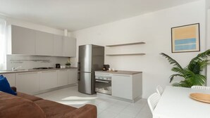 A modern kitchen with white cabinets, a stainless steel refrigerator, and a dining area with a white table and chairs. - 8th floor - Milano view (Milan)