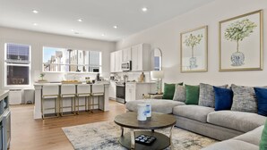 Une cuisine moderne avec des meubles blancs, un îlot central et un coin repas équipé de tabourets de bar.