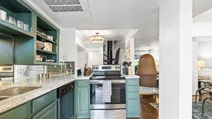 Una cocina moderna con armarios color turquesa, electrodomésticos de acero inoxidable y encimera de mármol.