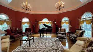 A spacious living room with a grand piano, elegant furniture, and large windows. - Harmony Hall at The Grange, Luxury Estate in Virginia Wine Country (Haymarket)