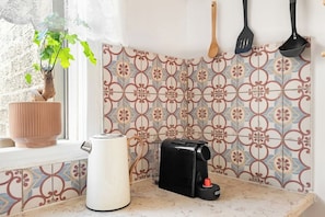 A kitchen with a coffee maker, a toaster, and a hanging utensil rack.