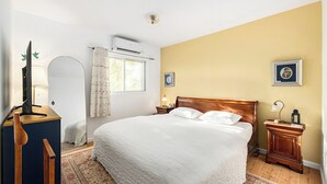 A bedroom with a large bed, a bedside table, a lamp, a picture frame, and a window with curtains. - Timeless Charm, Stunning Views & Serene Comfort (Jerusalem)