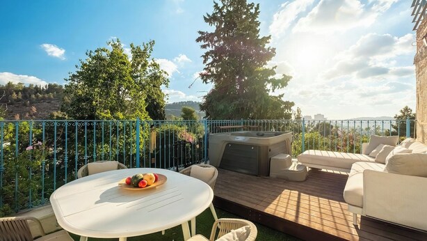 An outdoor patio with a round table, seating, and a hot tub. - Timeless Charm, Stunning Views & Serene Comfort (Jerusalem)