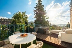Eine Terrasse im Freien mit einem runden Tisch, Korbstühlen, einer Couch und einem Whirlpool.