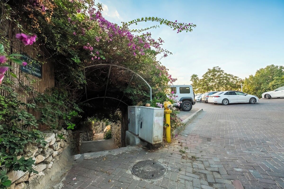 Un espace de stationnement doté d’une entrée abritée, d’un mur en pierre et d’un véhicule.