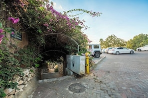 A parking area with a covered entrance, a stone wall, and a vehicle.