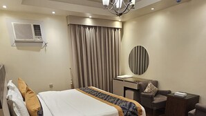 Una habitación de hotel con cama, escritorio, silla, espejo y ventilador de techo.