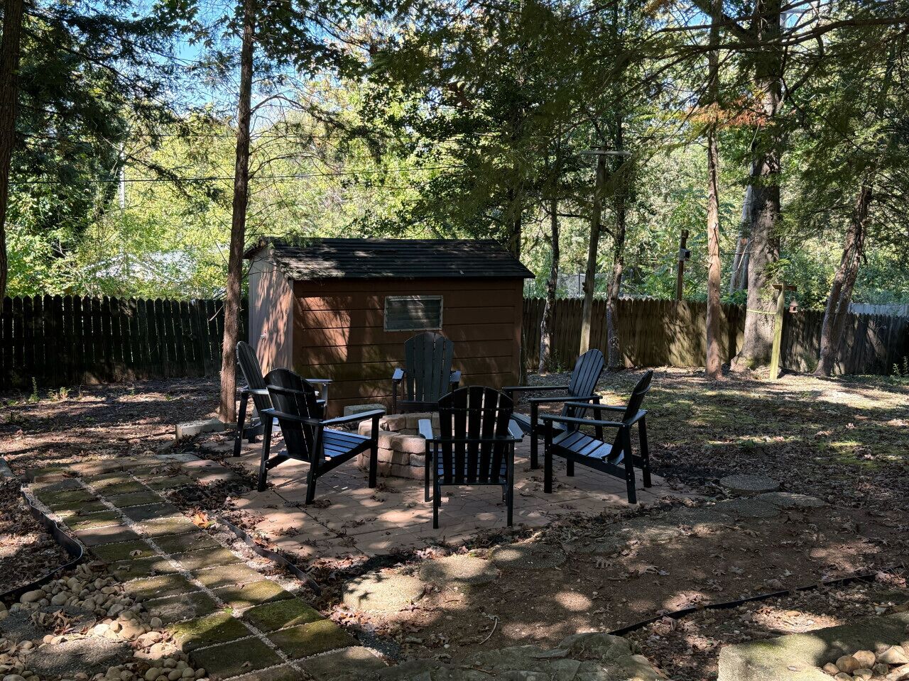 Una cabaña de madera con un pequeño patio, rodeada de árboles.