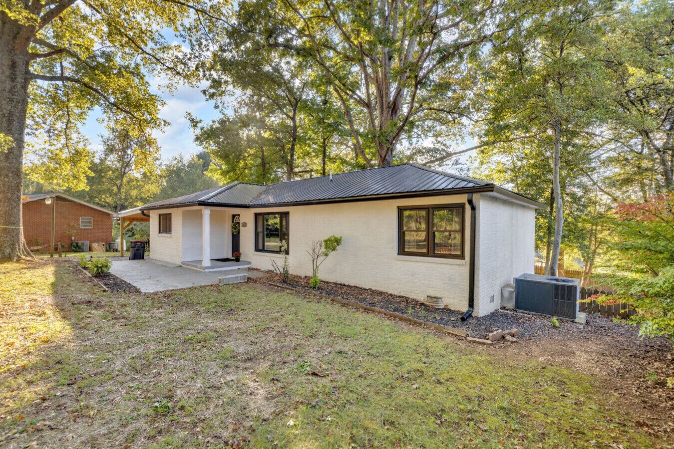 A single-story house with a covered porch, a small front yard, and a brick garage.