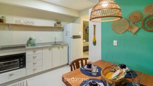 Una cocina moderna con horno empotrado, una mesa de comedor con cesta y una lámpara colgante.