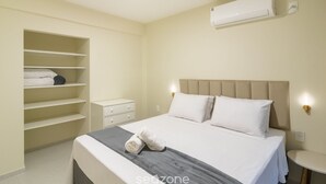 Un dormitorio con cama, armario, mesita de noche y aire acondicionado.