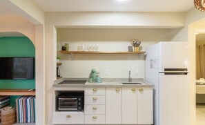 A modern kitchen with white cabinets, a built-in oven, a refrigerator, and a wooden shelf above the sink. - Apartment With 1 Suite 90 m From the Beach Sem0012 (Barra Velha)