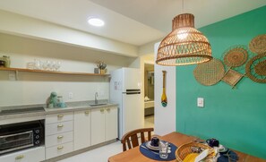 A modern kitchen with a built-in oven, a dining table with a basket, and a hanging light fixture. - Apartment With 1 Suite 90 m From the Beach Sem0012 (Barra Velha)