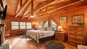 Ein gemütliches Schlafzimmer in einer Holzhütte mit Bett, Schminktisch und einem großen Fenster.