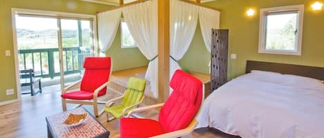 A bedroom with a bed, a table with a magazine, and two chairs.