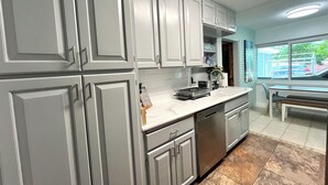 A kitchen with grey cabinets, a dishwasher, a sink, and a window with a view of the outside. - The Oasis at Lake Eva (Haines City)