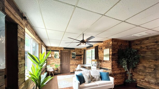 A spacious living room with a white sofa, wooden walls, and large windows. - The Oasis at Lake Eva (Haines City)