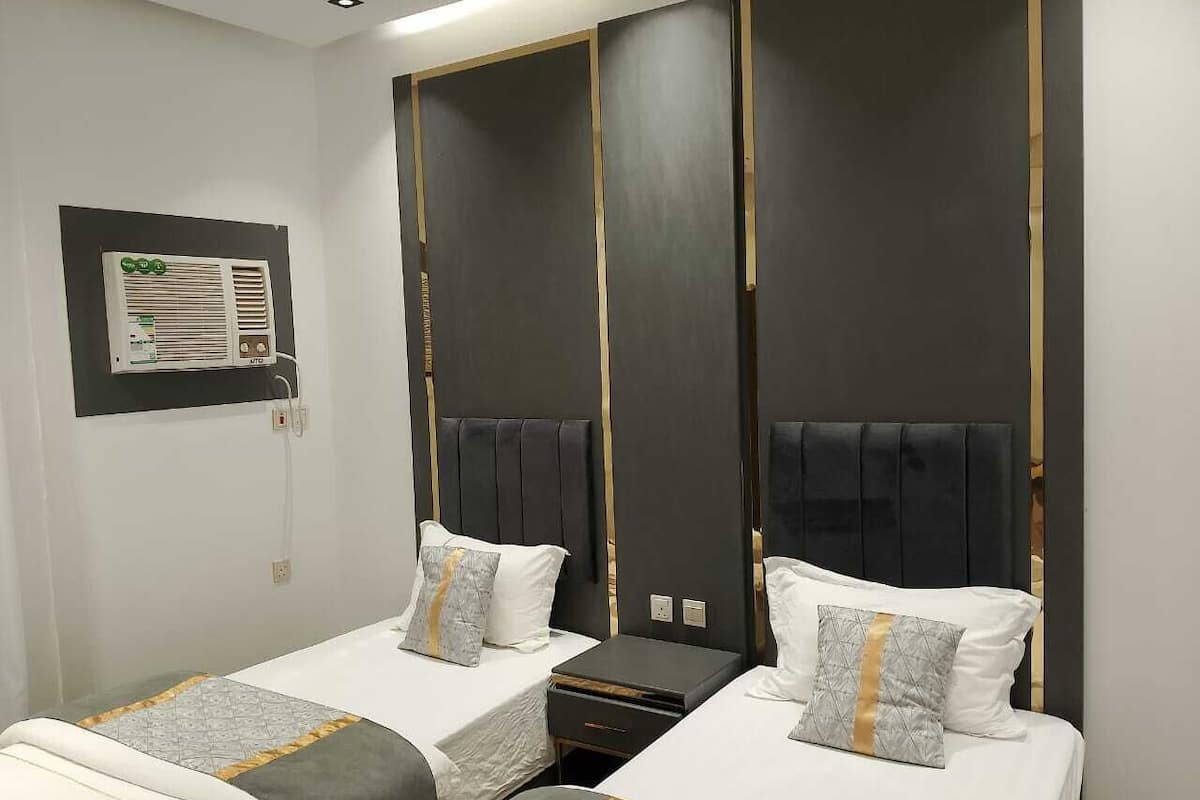 Hotellihuoneessa on kaksi sänkyä, joissa kummassakin on pääty ja yöpöytä. Vasemmalla seinällä on seinään kiinnitetty ilmastointilaite.