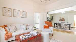 Una sala de estar con un sofá blanco, un aparador rojo y un comedor con una mesa y sillas.