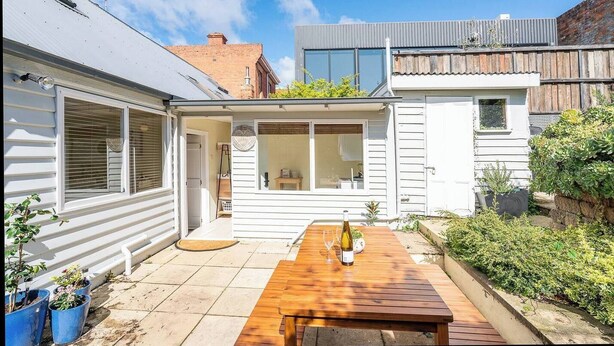 Una propiedad residencial con un patio, una mesa de madera y plantas en macetas.