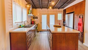 Eine Küche mit Holzschränken, einer großen Kochinsel und einer Pendelleuchte.