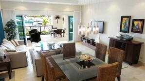 A modern living room with a dining area, a TV, and artwork on the walls.