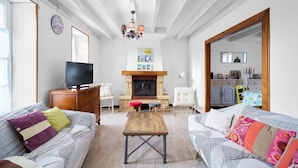 Una sala de estar con chimenea, sofá, televisor y una mesa de comedor.