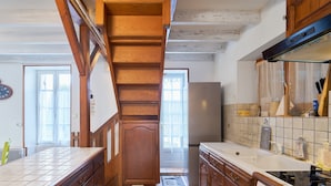 Una cocina con armarios de madera, salpicadero de azulejos, horno empotrado y refrigerador.