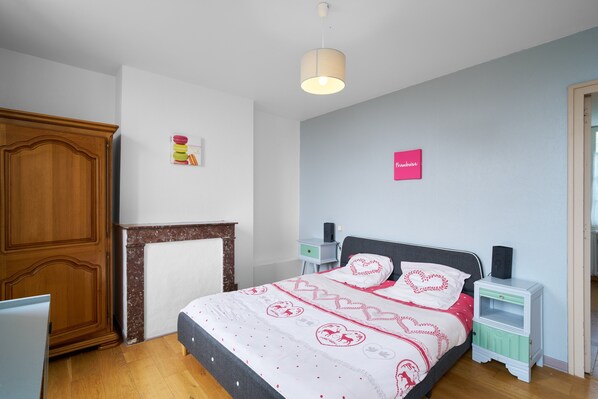 A bedroom with a bed, nightstands, a wardrobe, and a wall-mounted shelf.