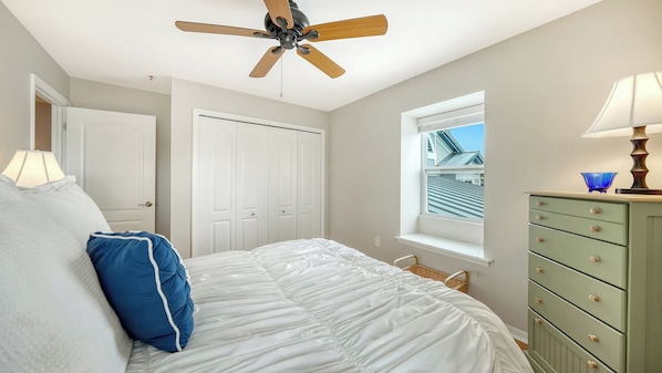 A bedroom with a bed, a ceiling fan, a window with a view, a dresser, and a lamp. - Heated Pool, FREE WIFI Luxury Bayside Condo Across from Siesta Key Beach | Beautiful 3BR/2BA Gulf & Bay Club Bayside Condo (Sarasota)
