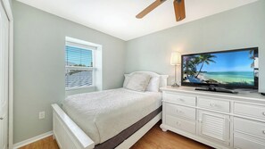 A bedroom with a bed, a TV on a dresser, a window with blinds, and a ceiling fan. - Heated Pool, FREE WIFI Luxury Bayside Condo Across from Siesta Key Beach |  Beautiful 3BR/2BA Gulf & Bay Club Bayside Condo (Sarasota)