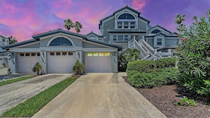 Une maison à deux étages avec un garage, une allée et une pelouse bien entretenue.