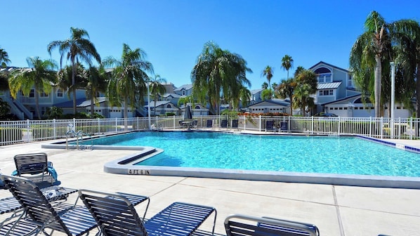 A swimming pool with lounge chairs and palm trees.